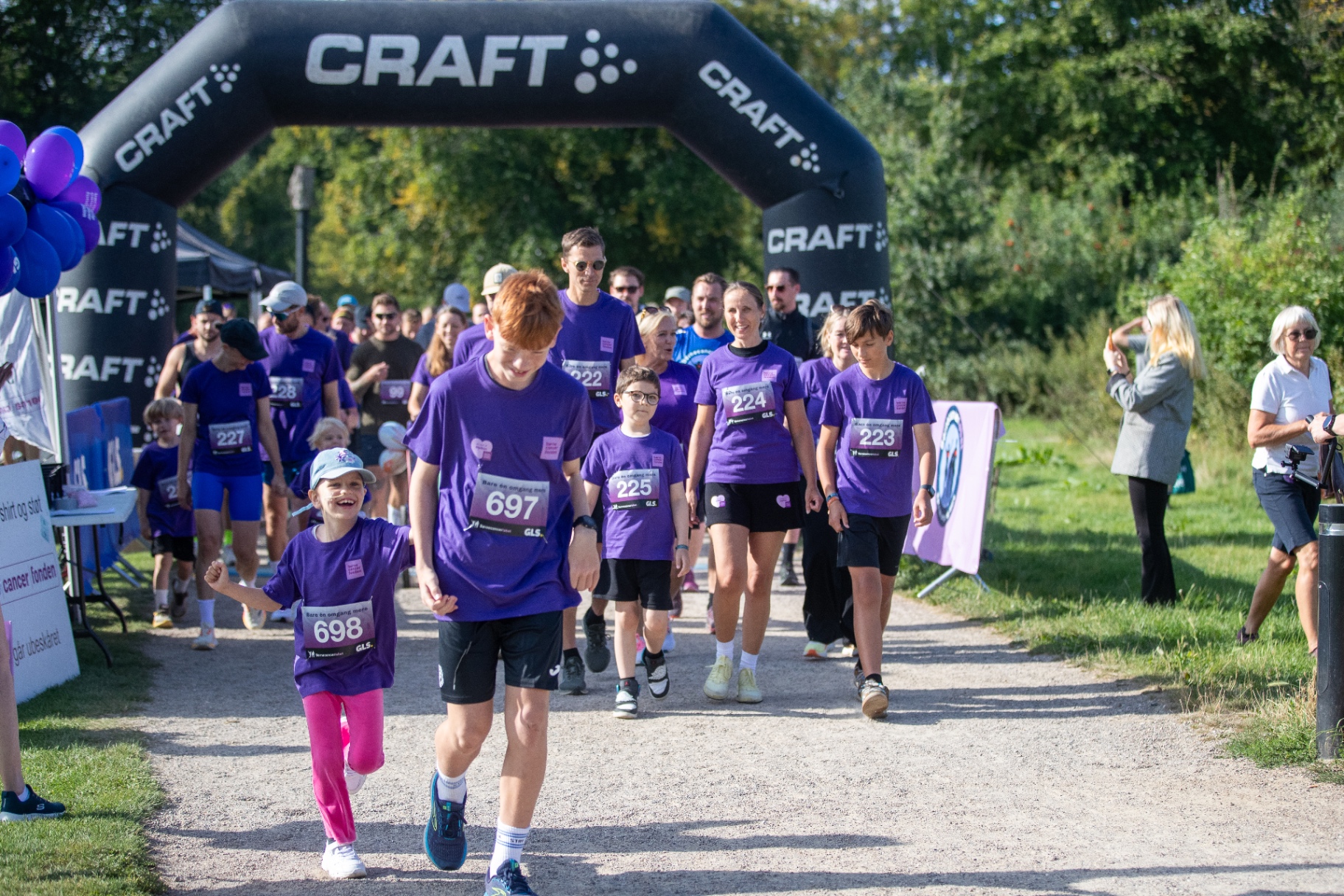Familier og børn går gennem startbuen til FundRacers-event